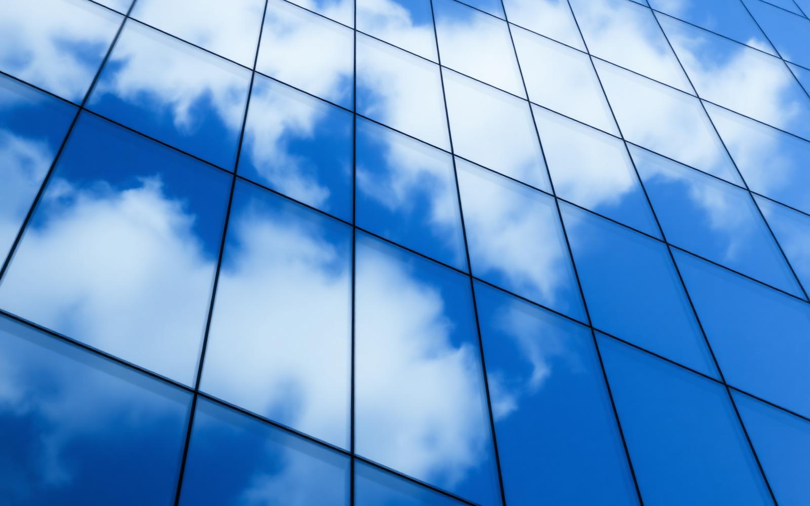 Reflective glass facade with sky and clouds